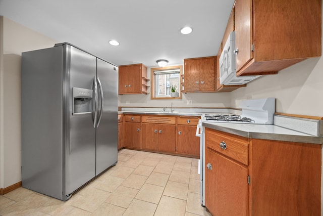 kitchen with brown cabinetry, white gas range, stainless steel refrigerator with ice dispenser, open shelves, and recessed lighting