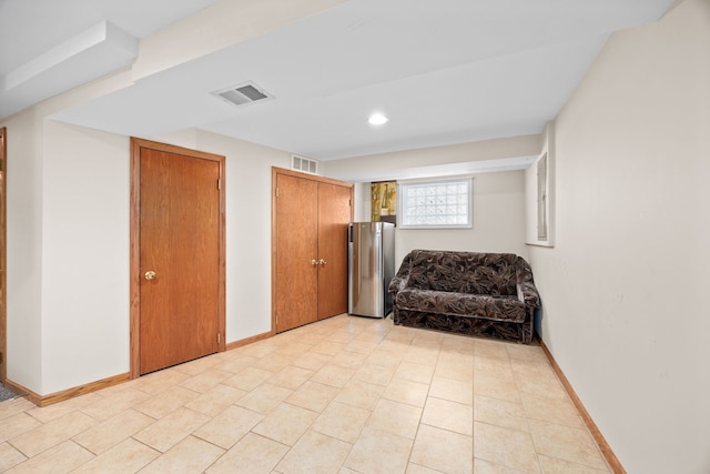 living area featuring light tile patterned floors, visible vents, and baseboards