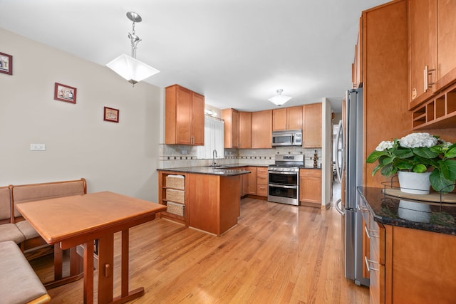 kitchen featuring stainless steel appliances, light wood-type flooring, a sink, and decorative backsplash