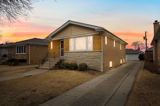 view of front of home with a garage, stone siding, brick siding, and an outdoor structure