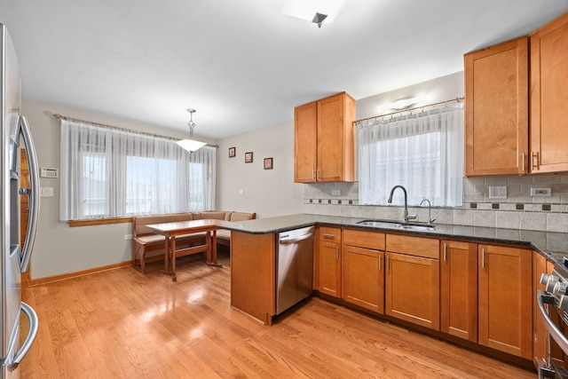 kitchen featuring brown cabinets, light wood finished floors, stainless steel appliances, and a sink