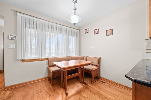 dining area with breakfast area, baseboards, and light wood finished floors