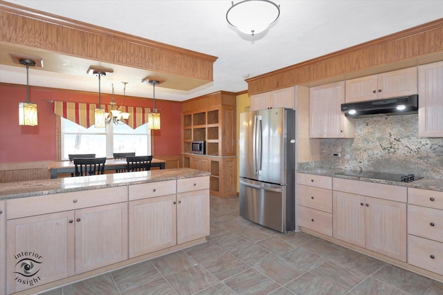 kitchen featuring under cabinet range hood, freestanding refrigerator, decorative backsplash, black electric stovetop, and a chandelier