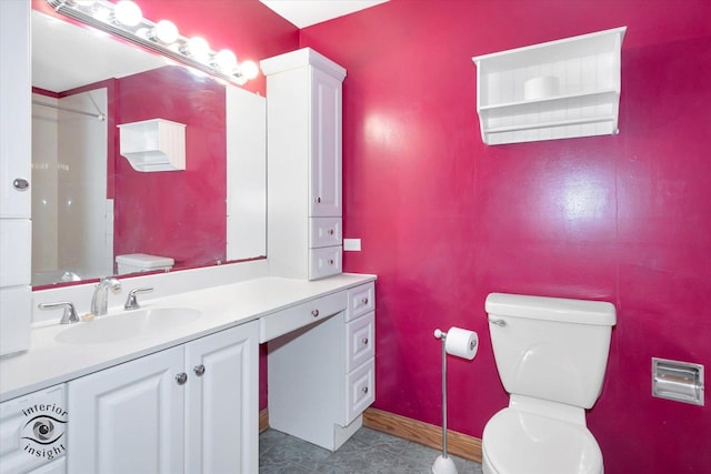 bathroom with toilet, vanity, and baseboards