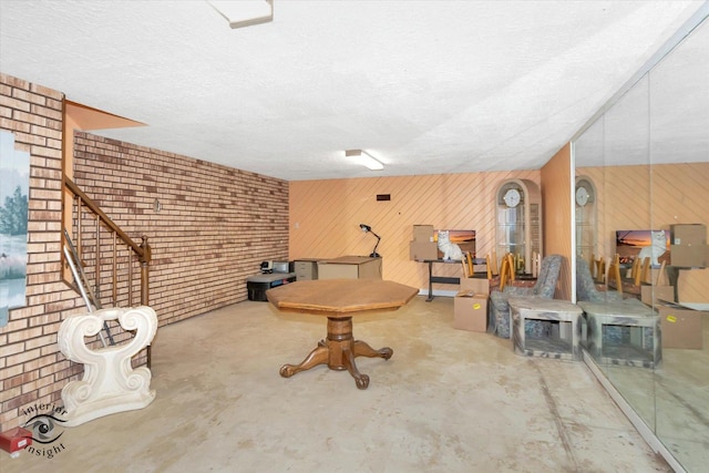 interior space featuring a textured ceiling, concrete floors, and wooden walls