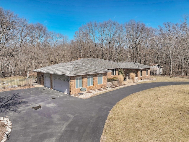 view of front of property featuring brick siding, fence, aphalt driveway, a front yard, and an attached garage