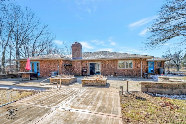 rear view of house featuring fence, french doors, brick siding, a chimney, and a patio area