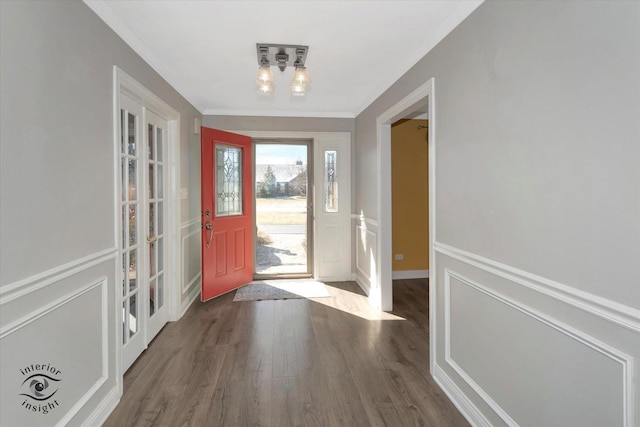 entryway with a decorative wall, wainscoting, crown molding, and wood finished floors