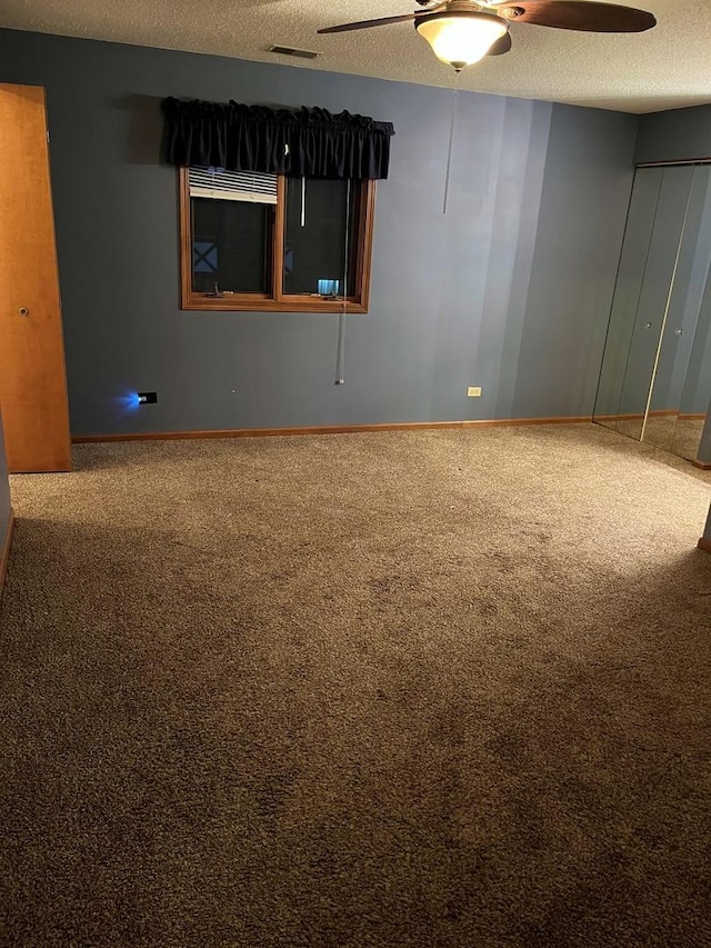 carpeted empty room featuring baseboards, a textured ceiling, visible vents, and a ceiling fan