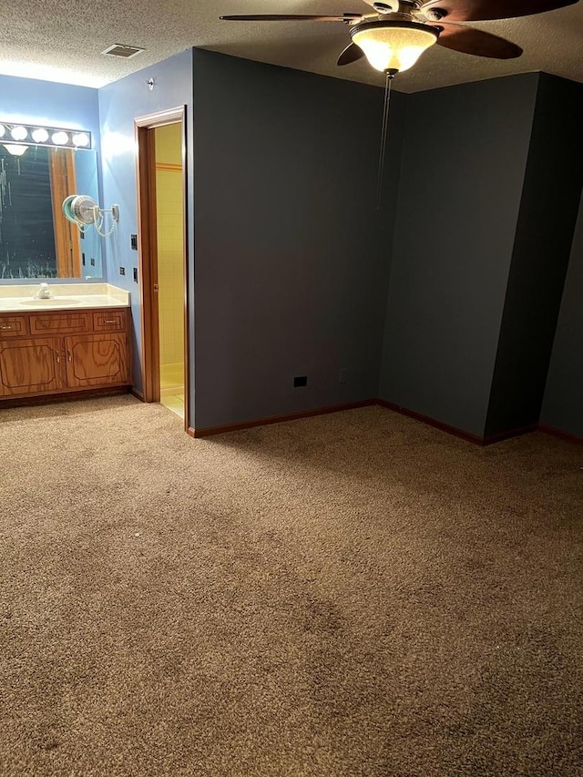 interior space featuring visible vents, light colored carpet, a sink, a textured ceiling, and baseboards