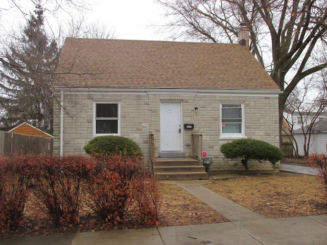 view of front of house featuring roof with shingles, a chimney, and fence