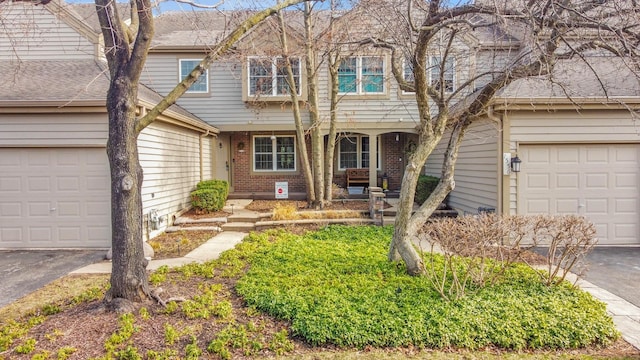 view of front of property featuring brick siding, aphalt driveway, and covered porch