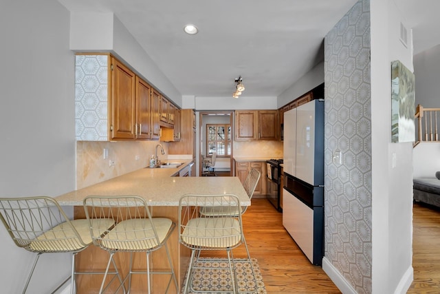 kitchen with light wood-style floors, light countertops, a sink, and freestanding refrigerator