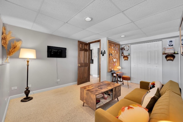 carpeted living area featuring a paneled ceiling and baseboards