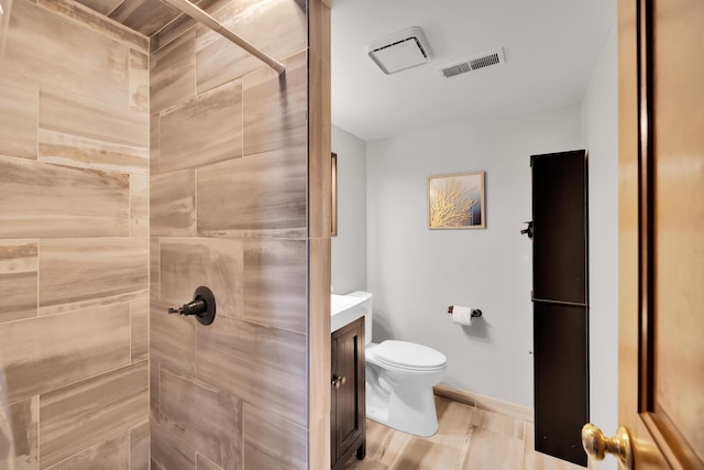 bathroom with visible vents, vanity, toilet, and tiled shower