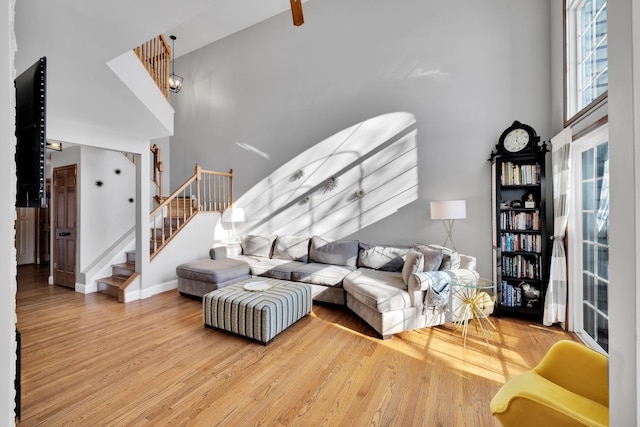 living room with a towering ceiling, stairs, baseboards, and wood finished floors