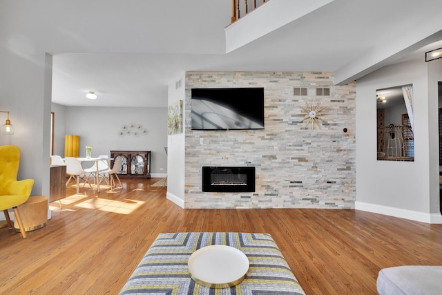 living area with a fireplace, baseboards, and wood finished floors