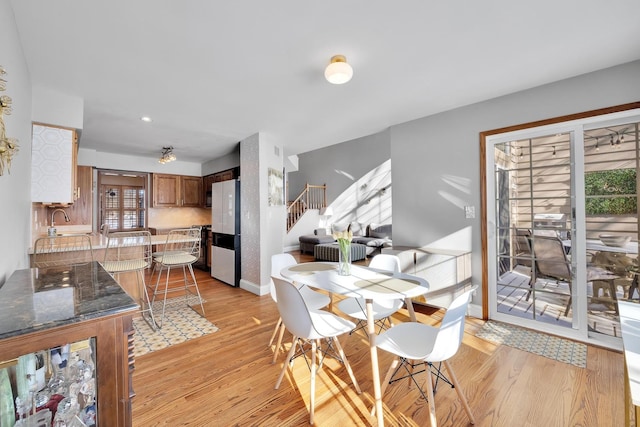 dining room with light wood-type flooring, baseboards, and stairs