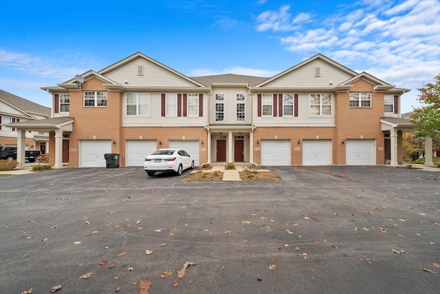 townhome / multi-family property with a garage, brick siding, and driveway