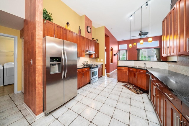 kitchen with under cabinet range hood, separate washer and dryer, a sink, appliances with stainless steel finishes, and tasteful backsplash