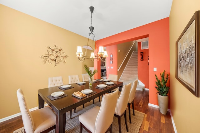 dining space with visible vents, wood finished floors, a chandelier, baseboards, and stairs