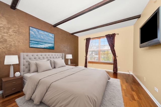 bedroom featuring baseboards, beamed ceiling, and wood finished floors