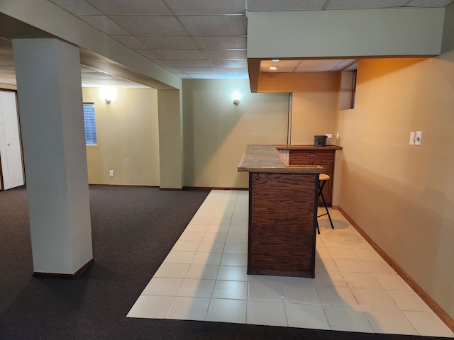 bar with a drop ceiling, a dry bar, baseboards, and tile patterned floors