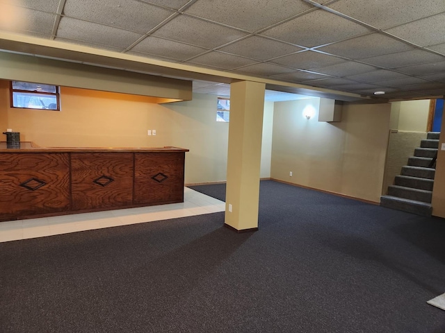 below grade area with stairs, baseboards, and a drop ceiling