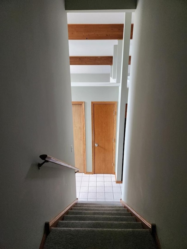 stairs featuring beamed ceiling and tile patterned flooring