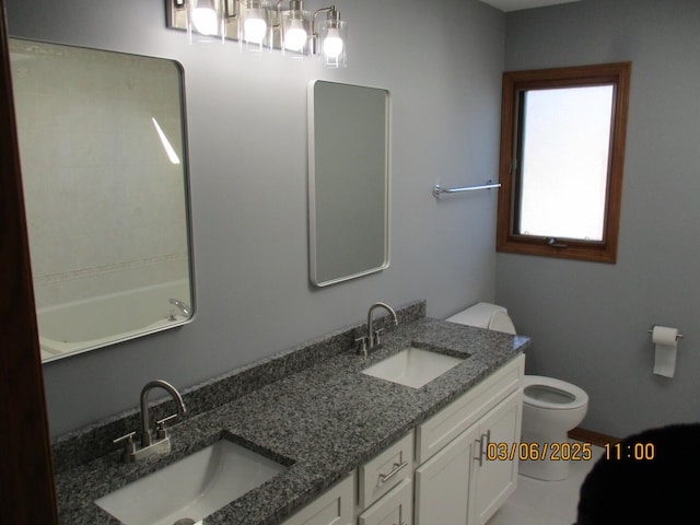 bathroom with double vanity, a sink, and toilet