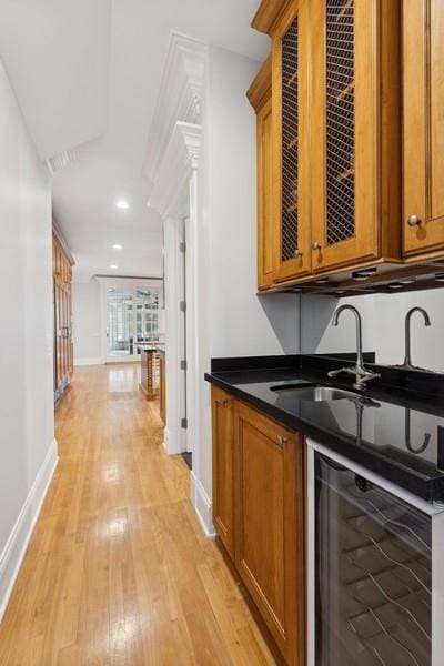 bar featuring wine cooler, light wood finished floors, baseboards, and a sink