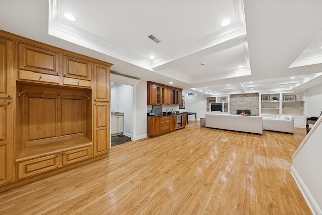 kitchen featuring visible vents, brown cabinets, a fireplace, and a raised ceiling