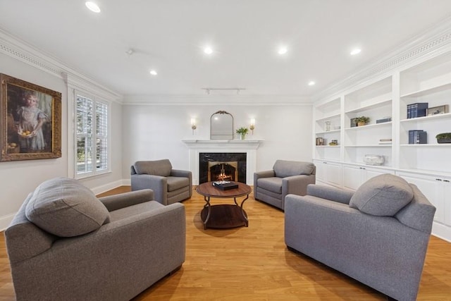 living area featuring light wood finished floors, baseboards, a high end fireplace, and ornamental molding