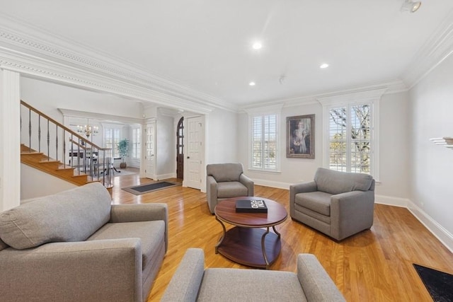 living room with stairs, crown molding, wood finished floors, and a wealth of natural light