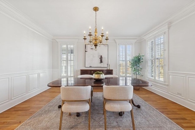 dining room featuring a healthy amount of sunlight, light wood-style floors, and ornamental molding