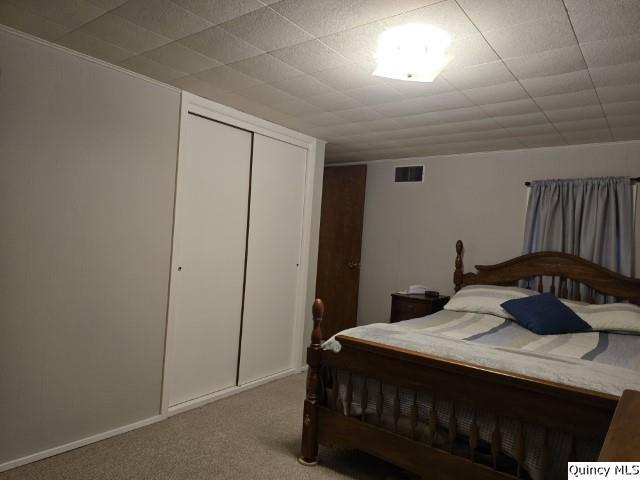 carpeted bedroom with a closet and visible vents