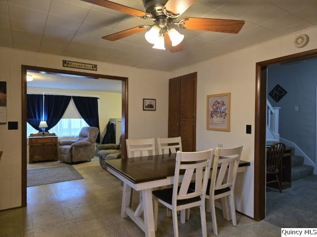 dining space featuring ceiling fan and stairway