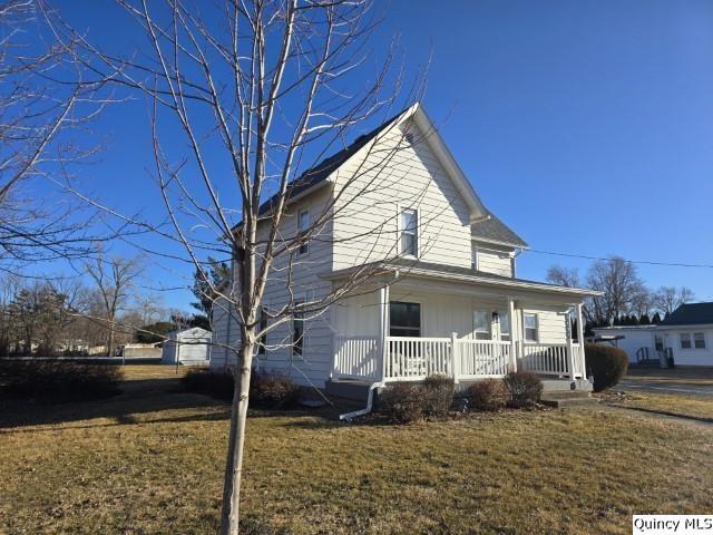 view of side of home with a porch and a yard