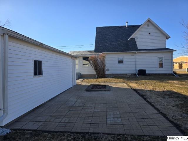 back of property with central AC, an outdoor fire pit, and a patio area