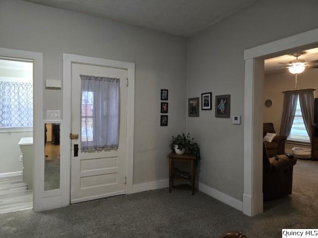 carpeted foyer entrance featuring baseboards and a ceiling fan