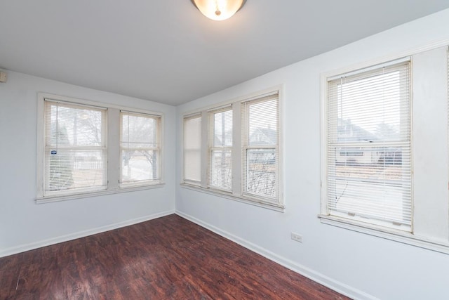 spare room featuring baseboards and dark wood finished floors