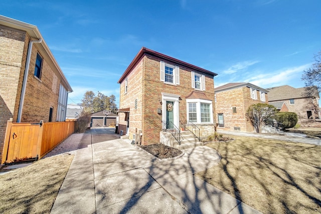 view of front of house with brick siding, an outdoor structure, driveway, and fence