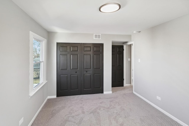 unfurnished bedroom featuring carpet, a closet, visible vents, and baseboards