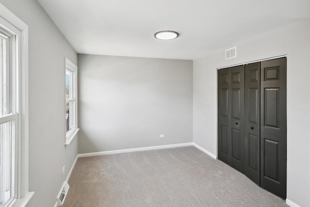 unfurnished bedroom featuring baseboards, a closet, visible vents, and carpet flooring