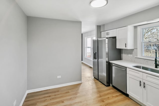 kitchen featuring appliances with stainless steel finishes, a wealth of natural light, white cabinets, and decorative backsplash