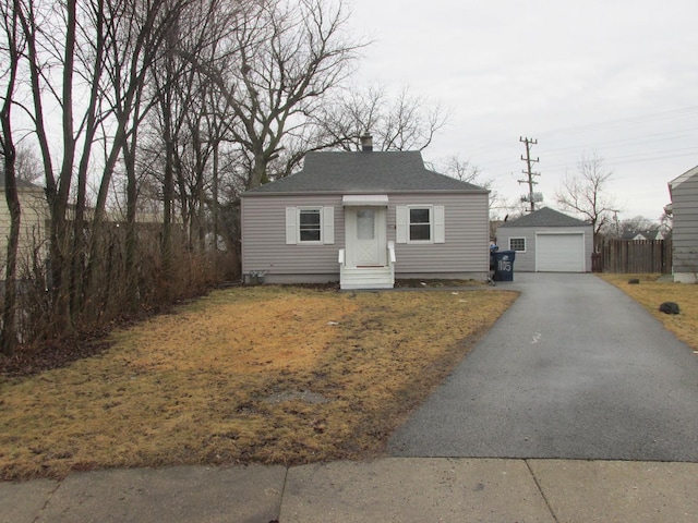 bungalow-style home featuring a garage, driveway, a shingled roof, and an outdoor structure