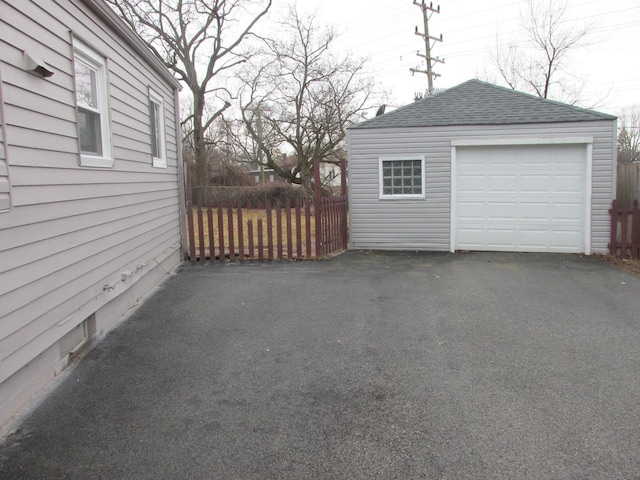 detached garage featuring fence and driveway