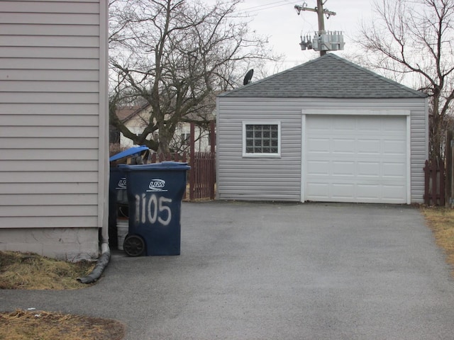 detached garage featuring aphalt driveway and fence