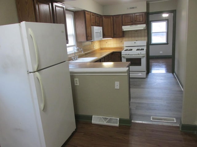 kitchen featuring white appliances, visible vents, a sink, and under cabinet range hood