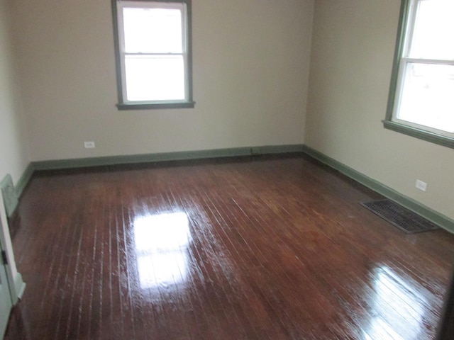 unfurnished room featuring baseboards, wood-type flooring, visible vents, and a wealth of natural light